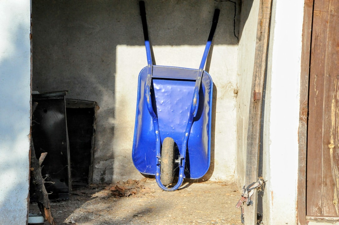 A blue wheelbarrow hanging from the side of a building